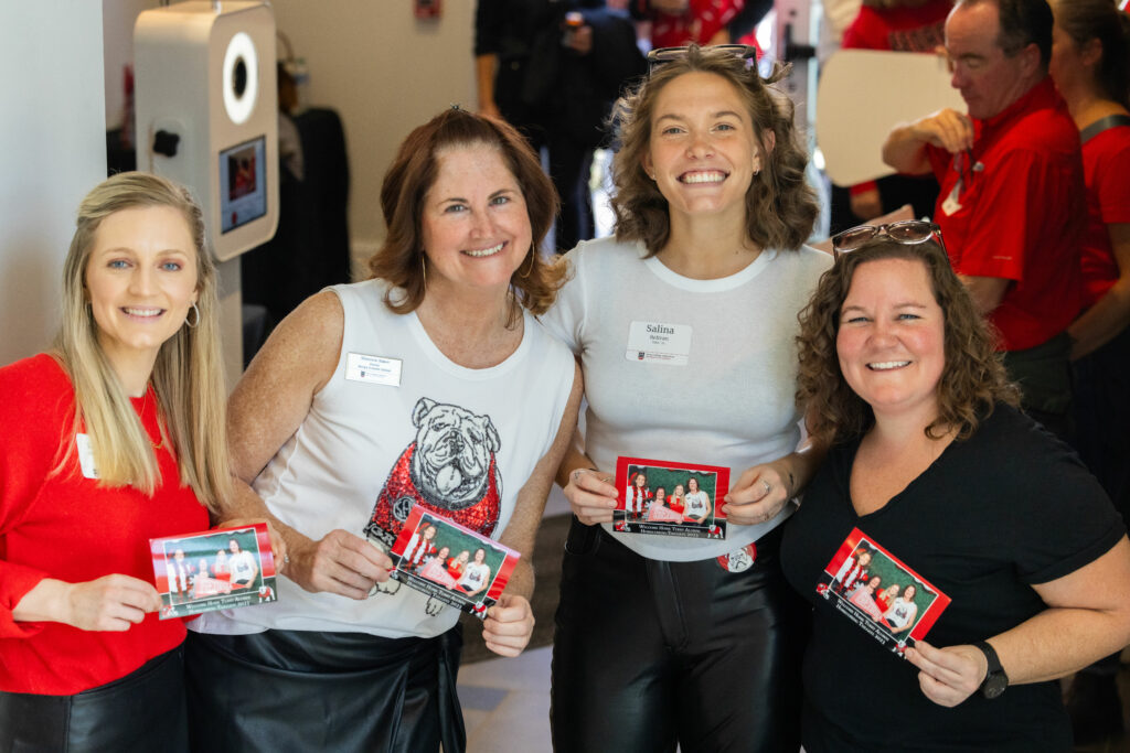 4 women standing together holding a picture and smiling