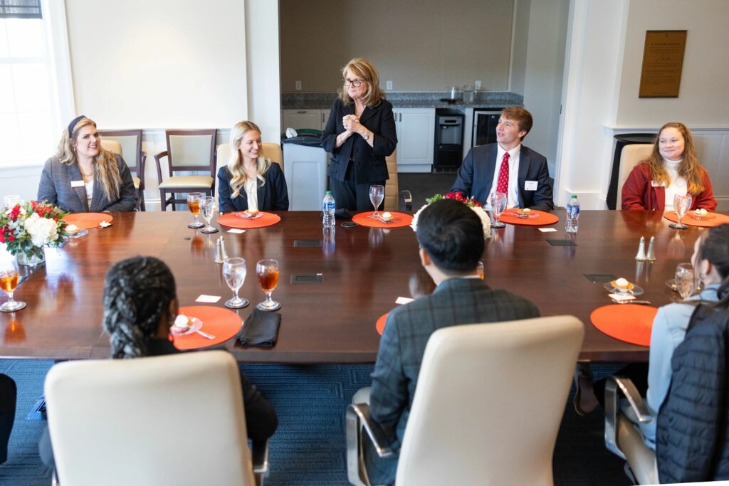 COX Communications COO Coleen Langner talks to students sitting around a conference table. 