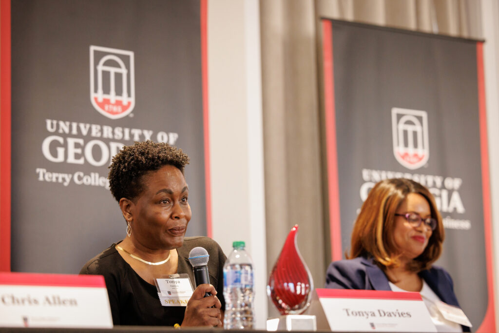 Tanya Davies listens to a students question during the 2024 Trailblazers roundtable with Terry College of Business banners behind her. 