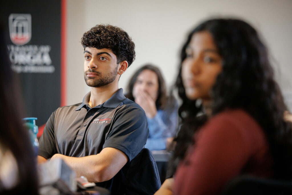 A male student in a Terry Diversity Fellows polo shirt watches The Terry Trailblazers roundtable on Feb. 3.