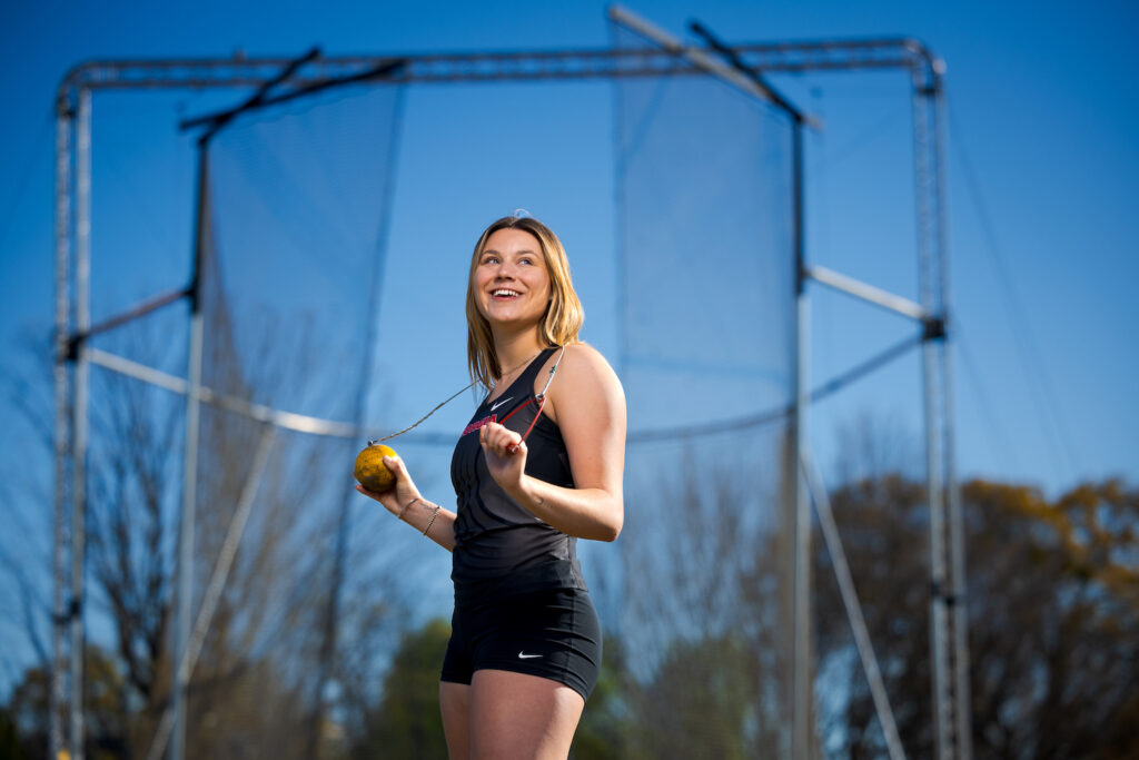 female student athlete with hammer (sporting tool) over shoulders