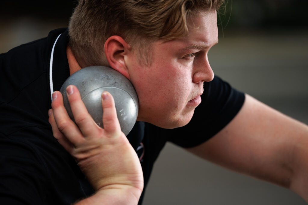 profile of student athlete holding shotput