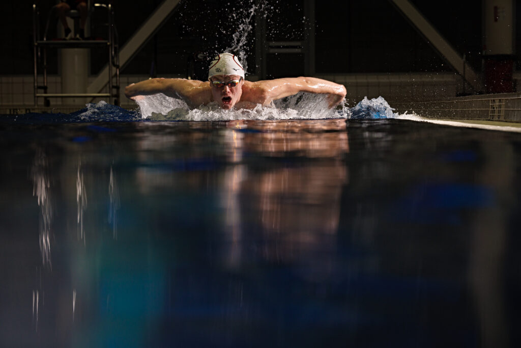 student athlete swimmer coming out of water using butterfly stroke