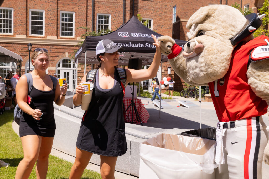 Students high five Hairy Dawg  at the Terry College Back to Business resource fair. 