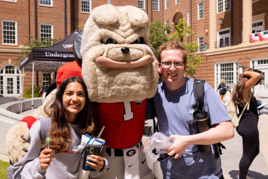 Two students pose with Hairy Dawg  at the Terry College Back to Business resource fair. 