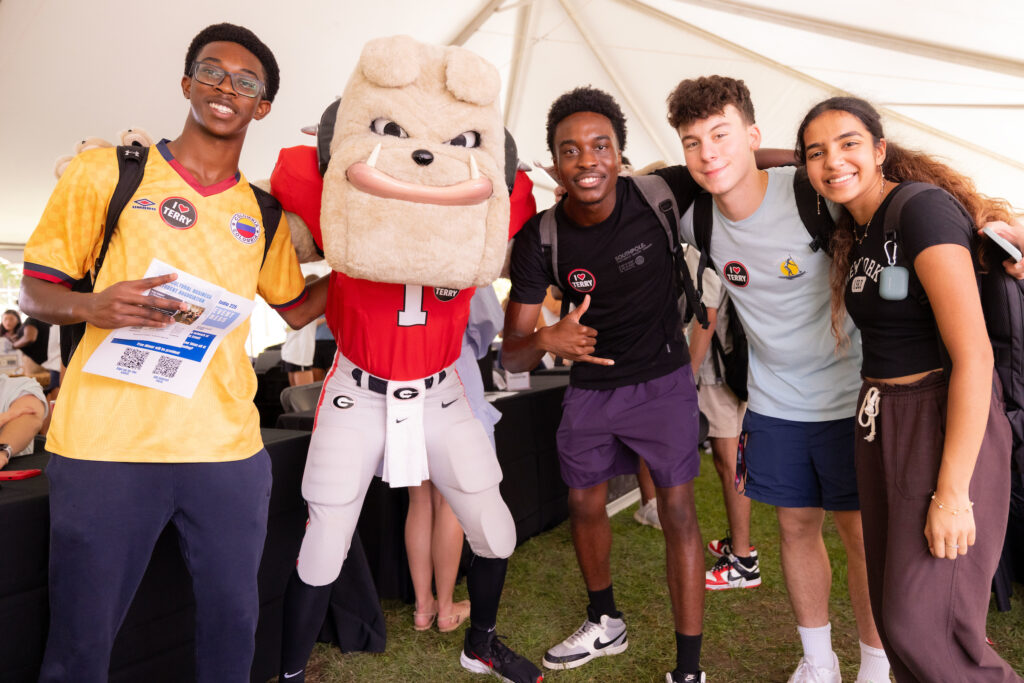 Two students pose with Hairy Dawg  at the Terry College Back to Business resource fair. 
