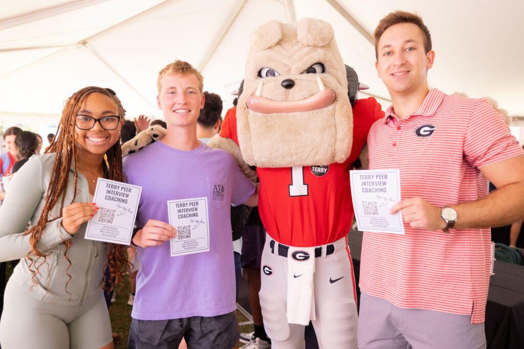 Two students pose with Hairy Dawg  at the Terry College Back to Business resource fair. 