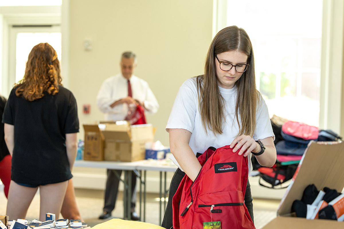 A female student packs a backpack to be donated to a homeless person