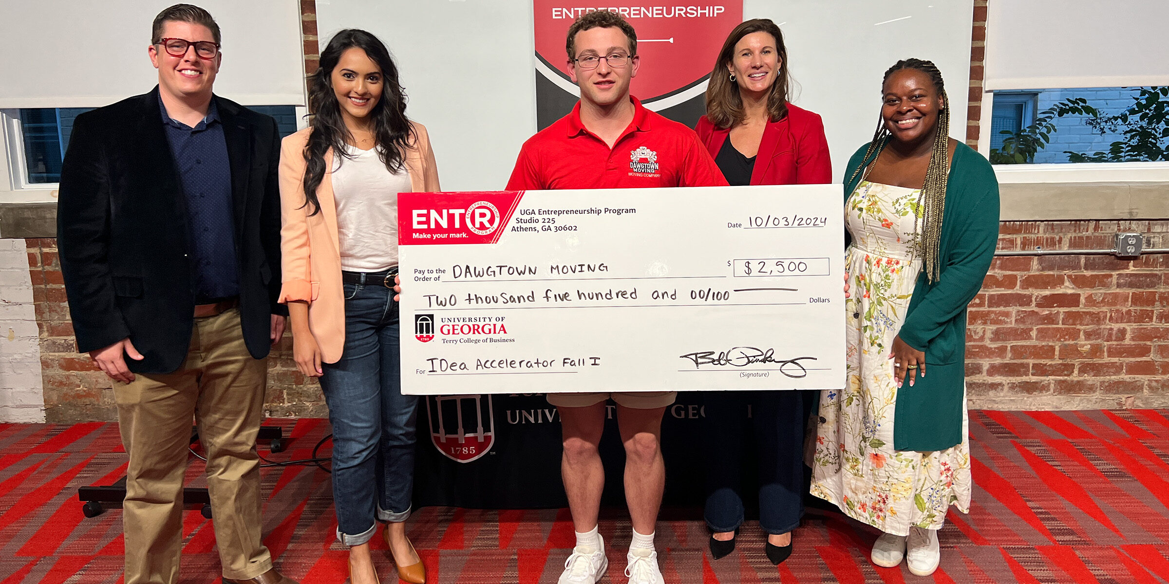Savannah native Clay Proper poses with a novelty check for $2500 and UGA Idea Accelerator judges at Studio 225.