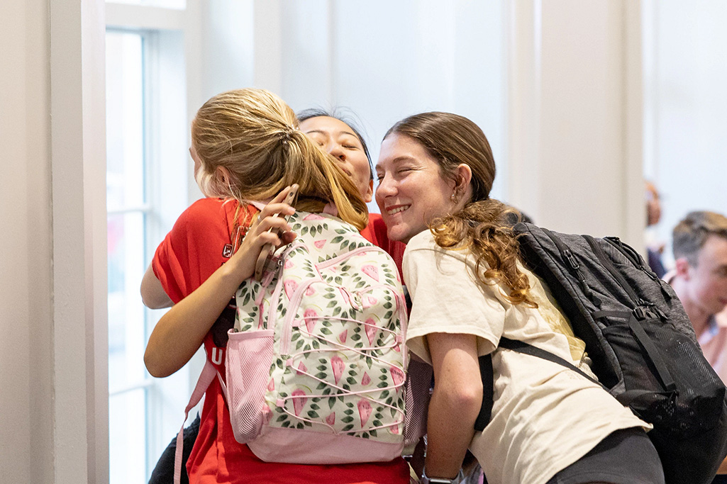 three students reunite with a hug