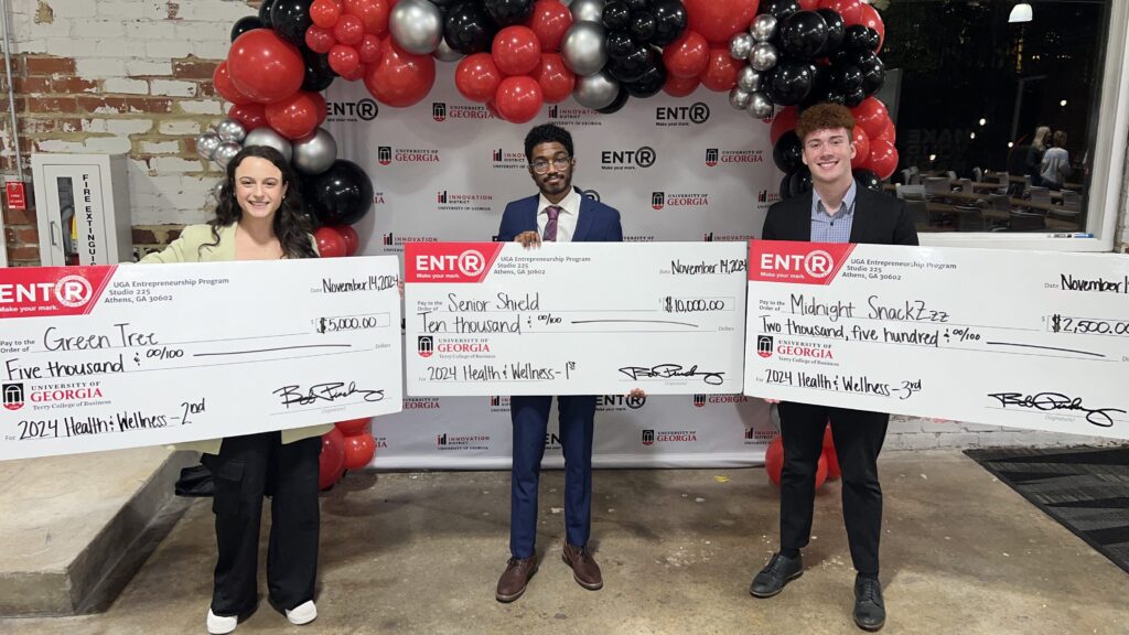 Kareem Elfoulie, Halle Greenbaum and Michael Hearnes stand in front of a sign that says pitch deck at Studio 225.
