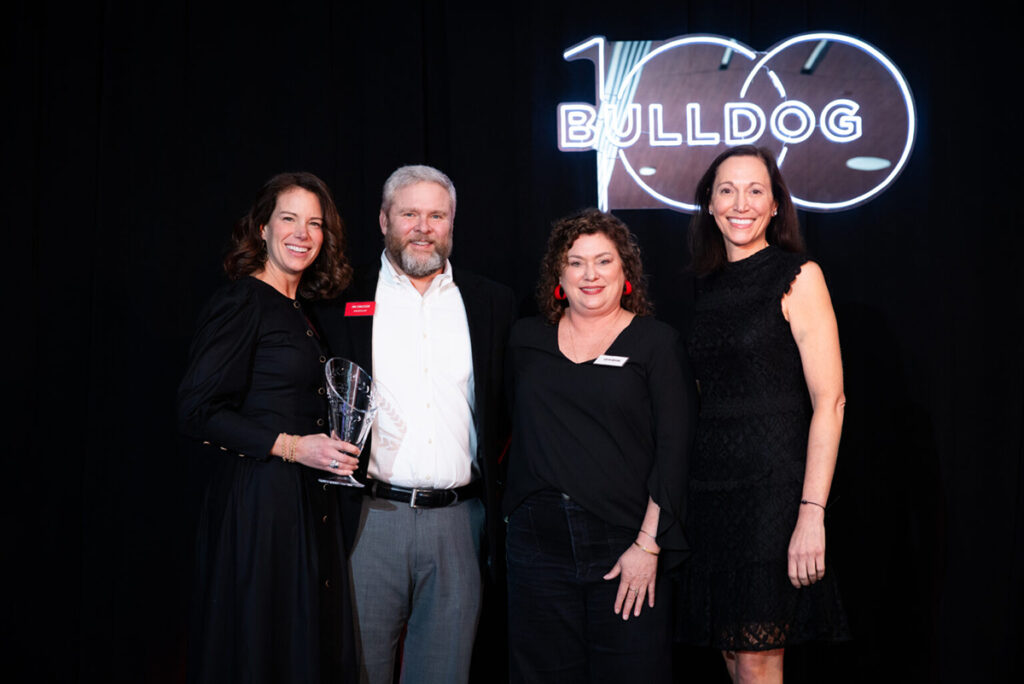Four people posing with an award