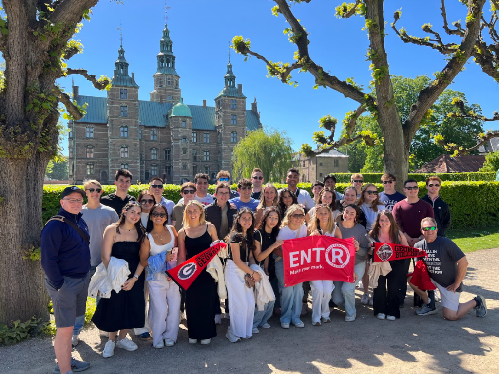 A group of Terry student studying abroad in Scandinavia holding a Georgia flag posing for a picture.