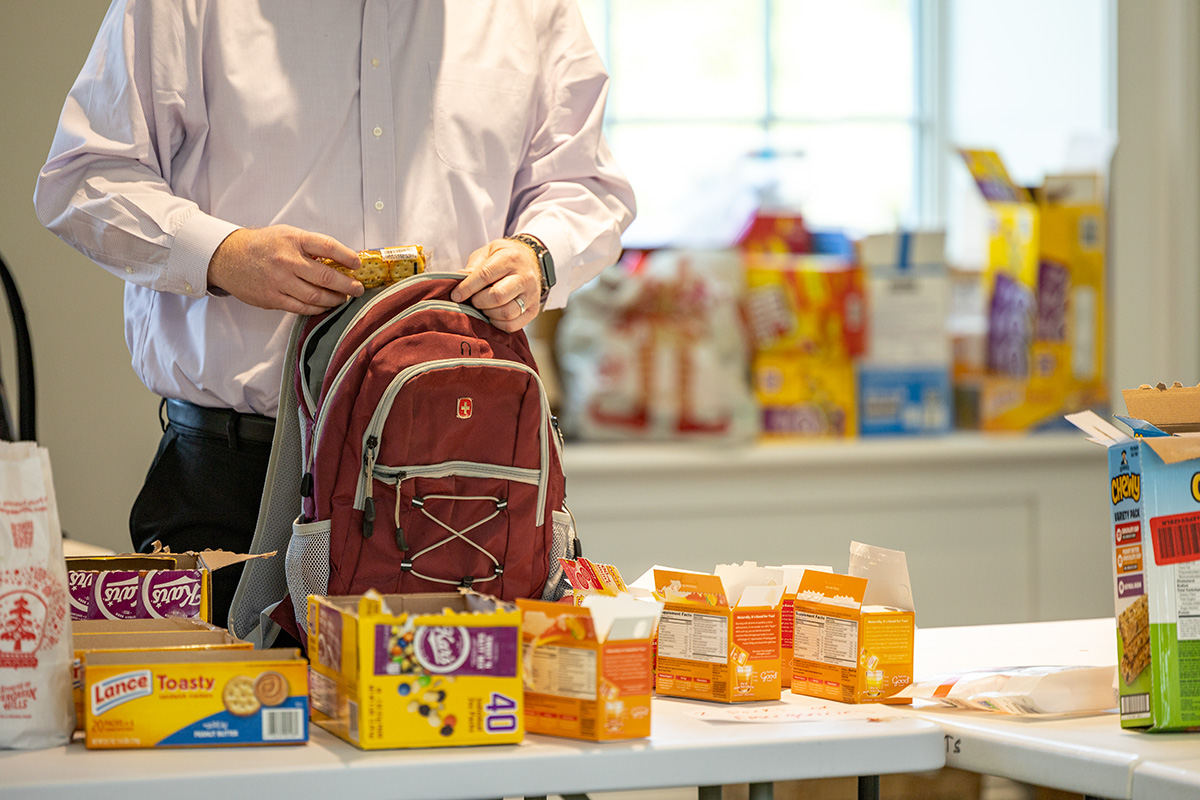 A man packs snacks into a backpack.
