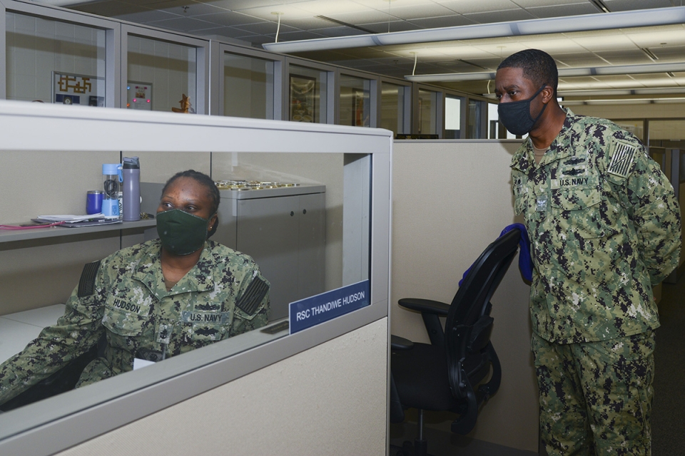 Capt. Milton Troy discusses the daily commander’s critical information requirements reports with Chief Retail Services Specialist Thandiwe Hudson. (U.S. Navy photo by Mass Communication Specialist 2nd Class Derien C. Luce)