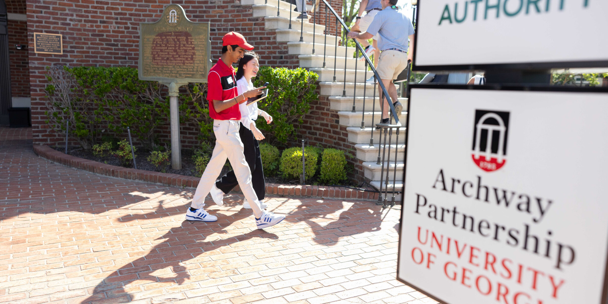 UGA students walk past an UGA Archway Partnership sign in downtown Waynesboro.